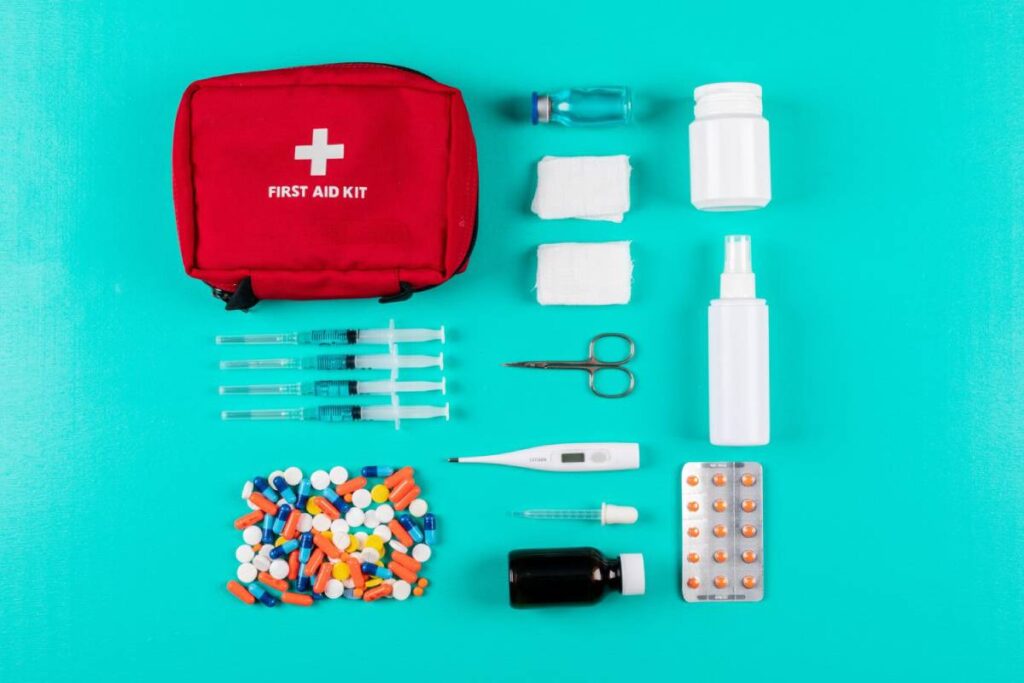 A variety of medical supplies and a red first aid kit on a teal background.